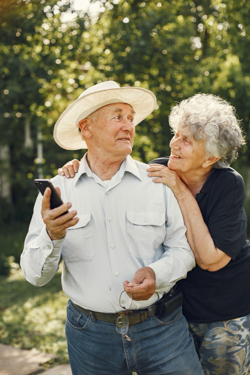 An older couple standing together in a sunlit garden