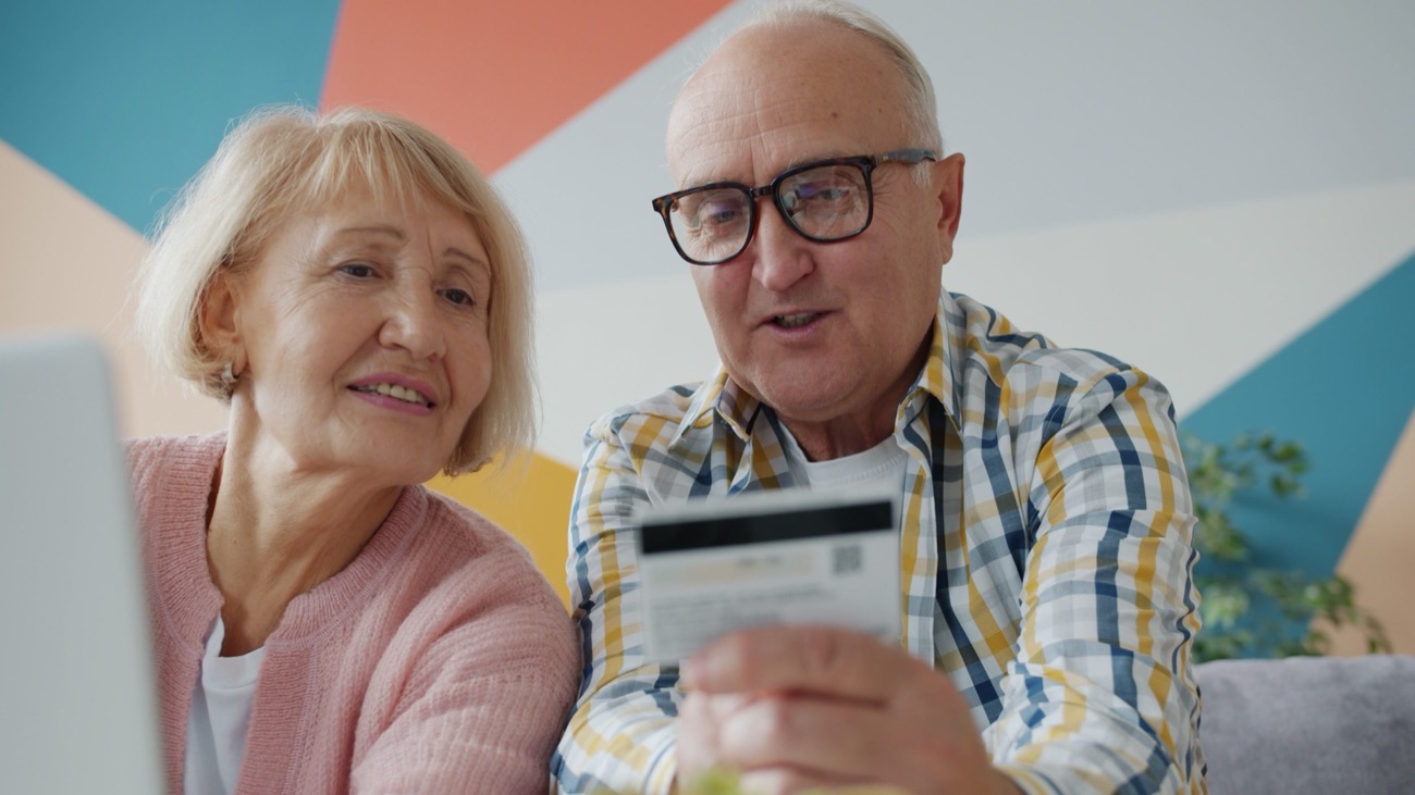An older couple sitting together at home looking at a laptop