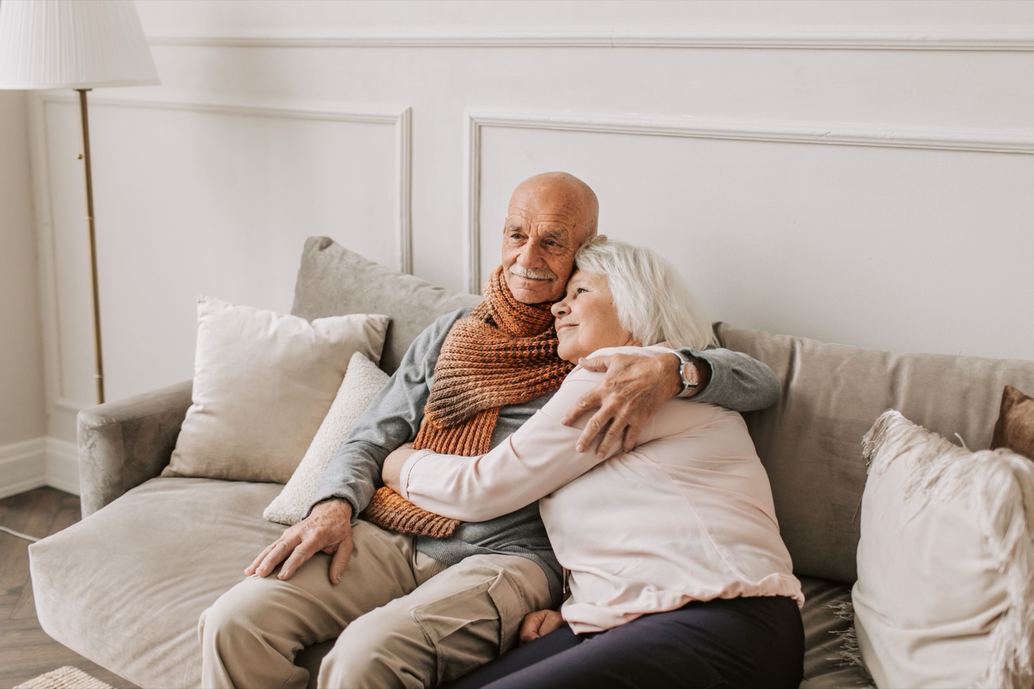 An older couple sitting close together on their sofa at home