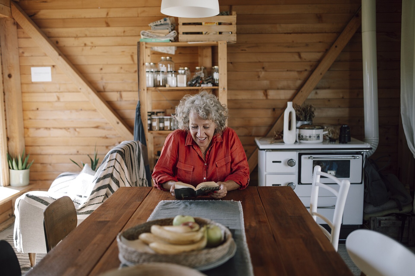 An older woman reading at her kitchen table