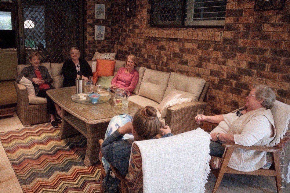 Older women and a visiting daughter relaxing on a brick patio